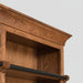 A large wooden bookcase with three bays, featuring dark wood hanging rods across the top of each bay and a matching dark wood ladder leaning against the center-left side, shown on a light gray background.
