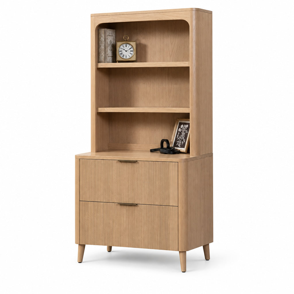 A mid-century modern wooden bookcase and drawer cabinet in a light oak finish, featuring three open shelves, two drawers, and tapered legs, shown against a plain white background.