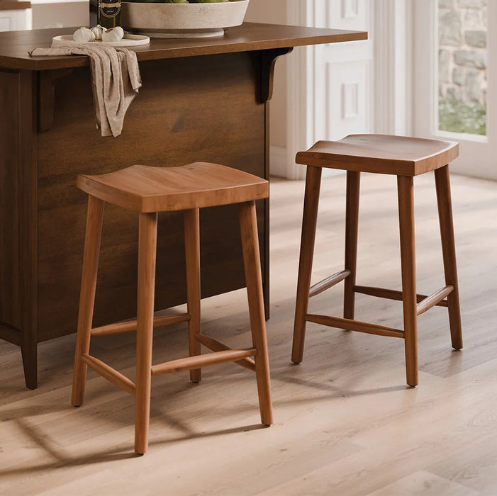 Two wooden bar stools with a warm medium-brown finish, shown in a bright kitchen setting next to a matching wooden island.