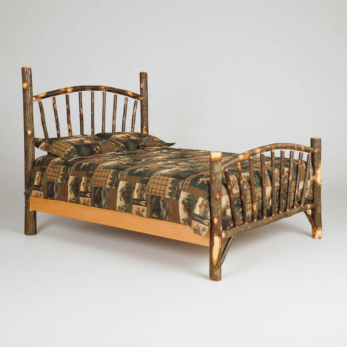 A rustic log cabin bed frame made from natural tree branches with curved headboard and footboard, shown with camouflage bedding on a plain white background.