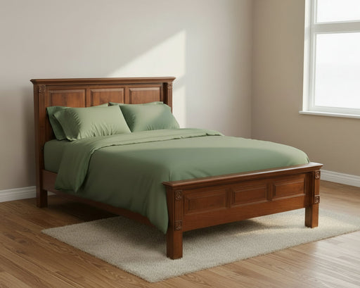 Wooden bed with green bedding in a room with a window.