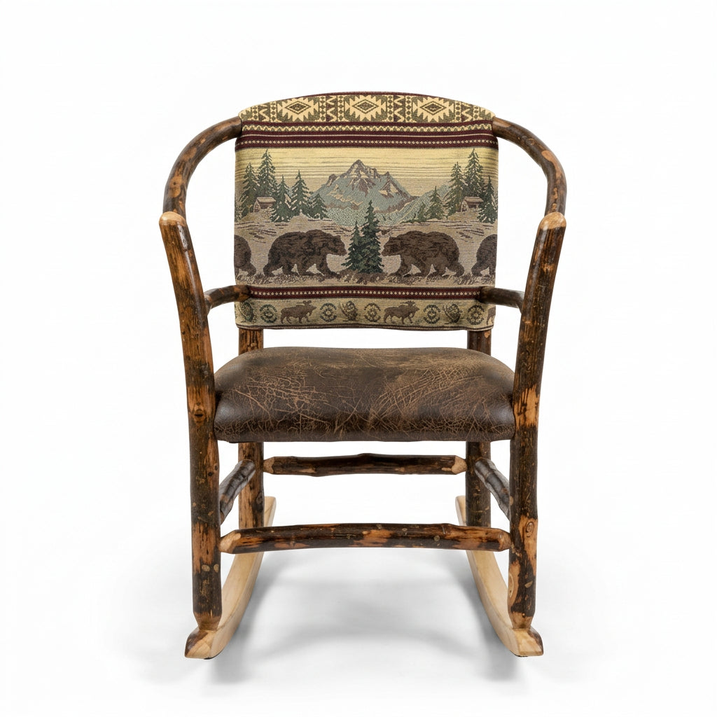 A rustic log-style rocking chair with a brown leather seat and a backrest featuring a green and beige bear and tree pattern, shown in a furniture store.