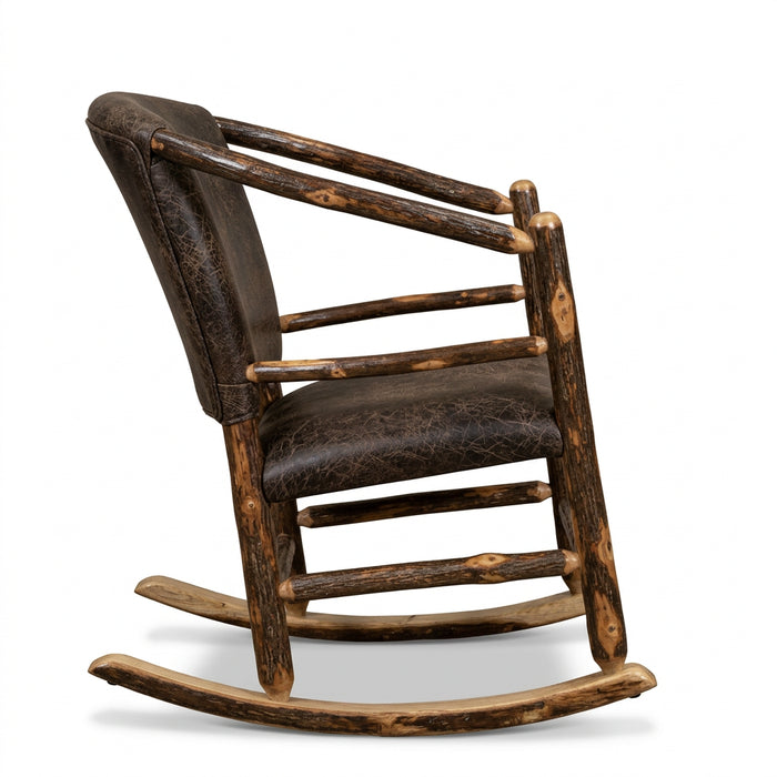 A rustic log-frame rocking chair with a distressed brown leather seat and backrest, positioned in a rustic shop interior with a black bear taxidermy mount and wood wall decor in the background.