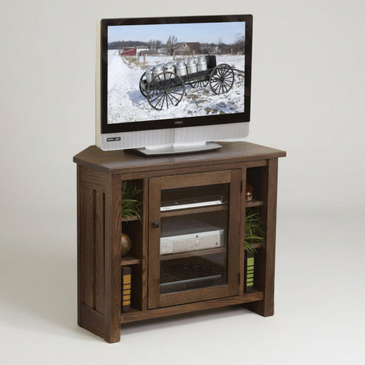 A rustic brown wooden TV stand with glass doors and open shelves, holding a television and electronic devices, set against a plain white background.