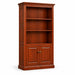 A tall wooden bookcase with a warm brown finish, featuring open shelves on the upper half and two cabinet doors on the lower half, styled with a vase, books, and a picture frame against a white background.