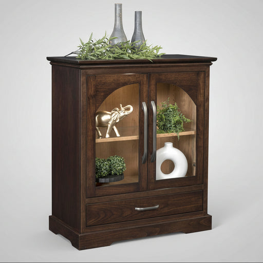 A dark brown wooden cabinet with two glass-front upper doors and a single drawer below, styled with decorative vases, greenery, and a small elephant figurine on a white background.