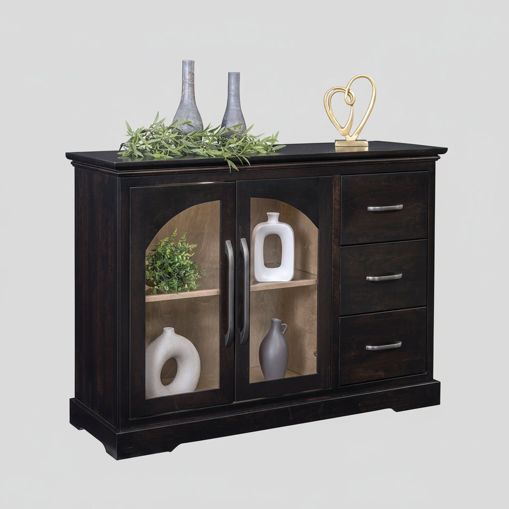 A dark wood sideboard cabinet with two glass-front doors and three drawers, styled with decorative vases, greenery, and a gold heart sculpture on a white background.