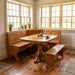 A wooden corner booth set with a matching pedestal table, featuring a warm medium-brown oak finish and built-in benches on a white studio background.