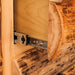 Close-up of a rustic log furniture piece with a metal drawer slide mechanism, showing natural wood grain and bark details against a white background.