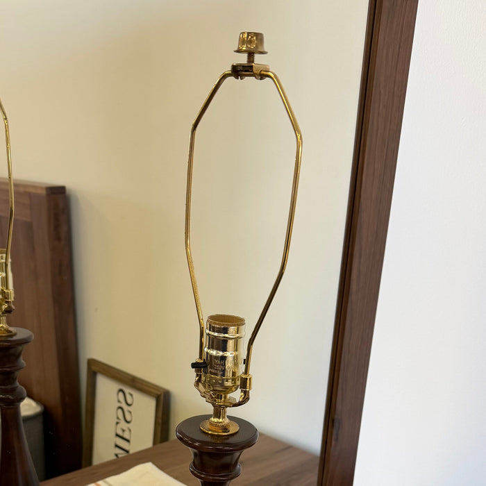 Wooden floor lamp with gold base and shade on a striped rug.