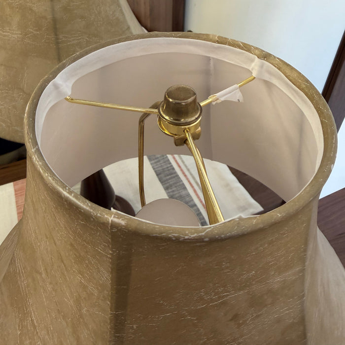 Close-up of a lamp with a beige shade and gold fixture.