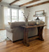Wooden console table in a furniture store setting with sofas and decor items.
